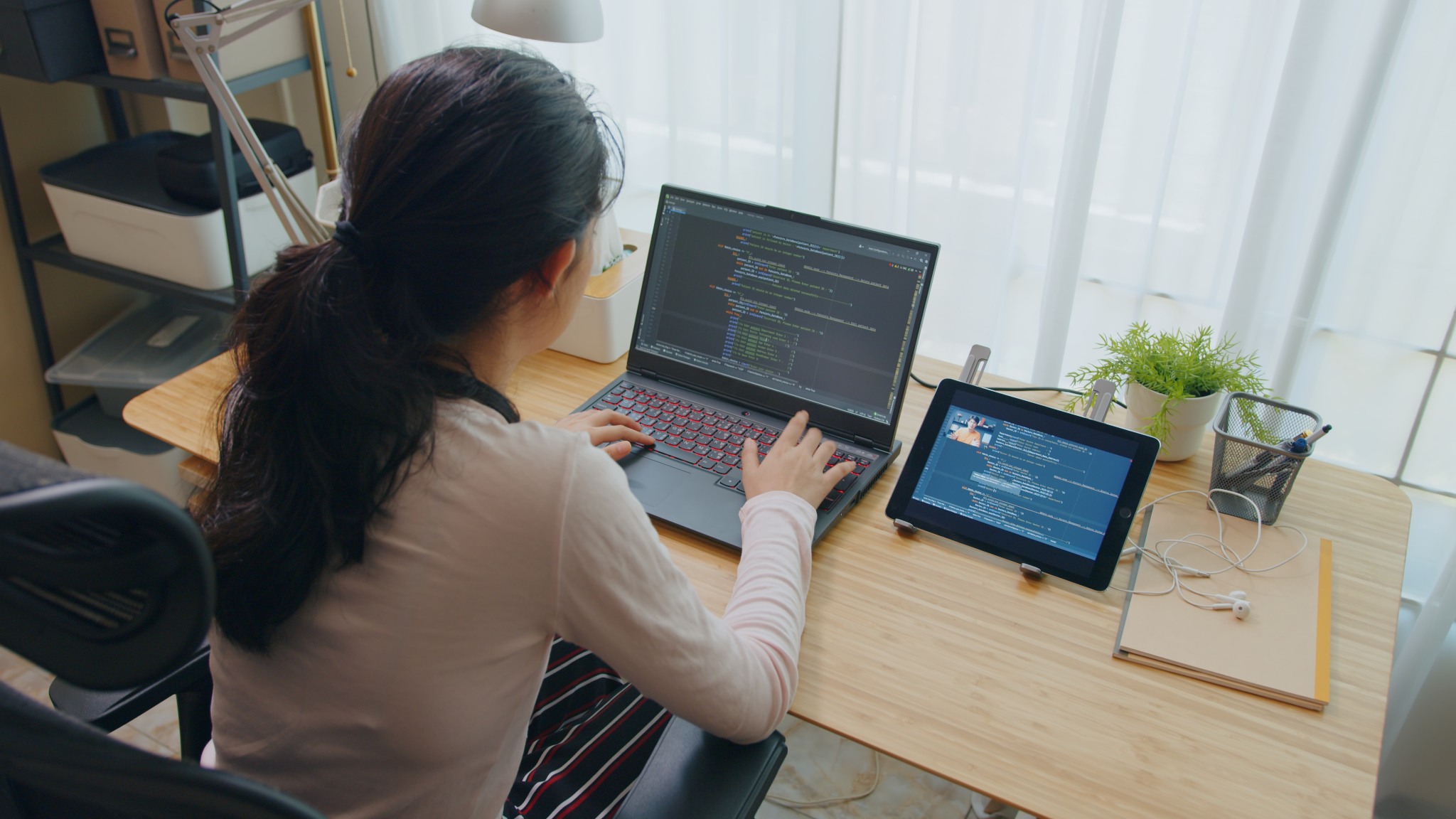 One student sitting at a desk coding on their computer