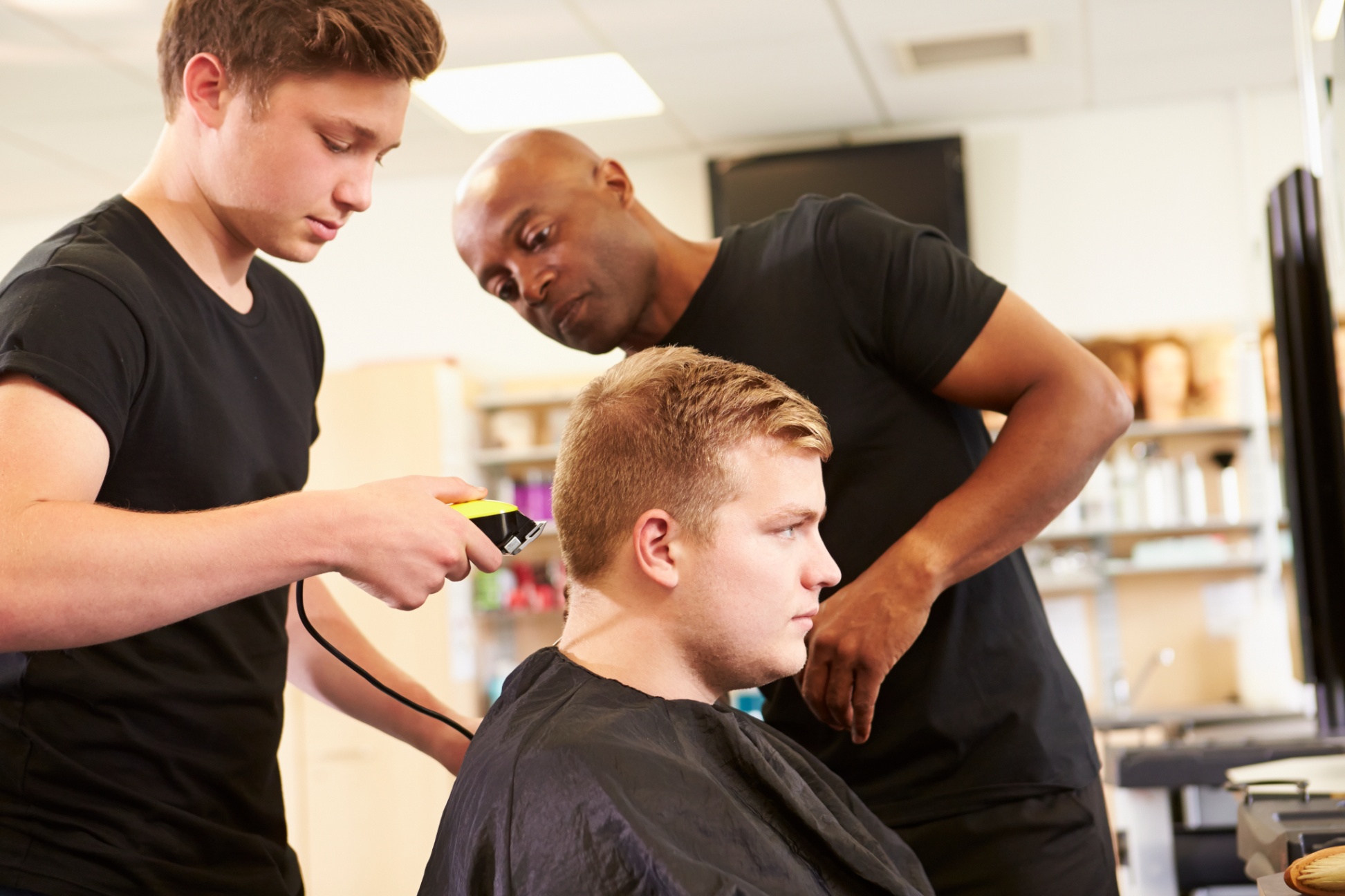 Three hairstyling students working on short haircut