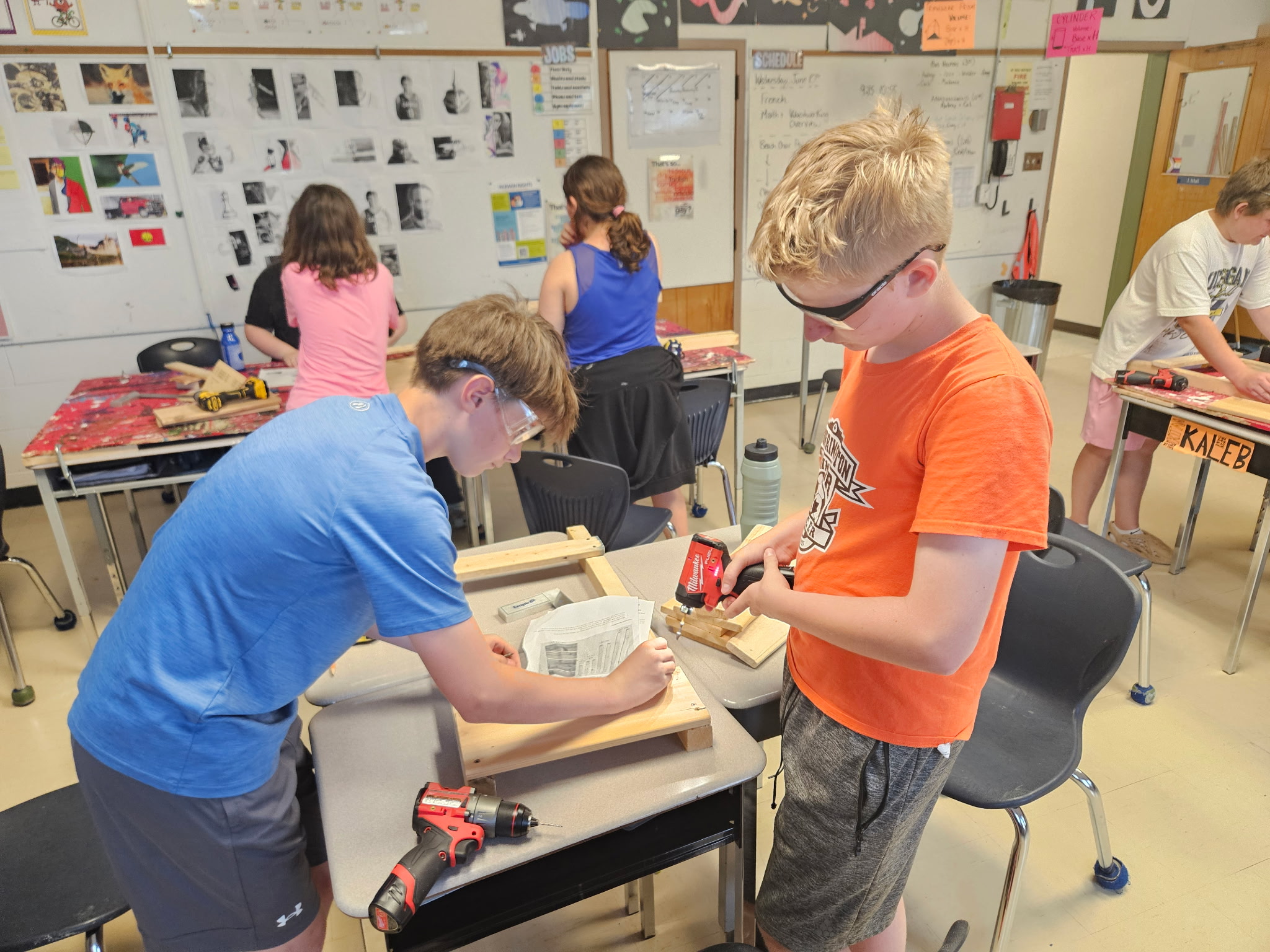 Several students in a classroom building a folding chair