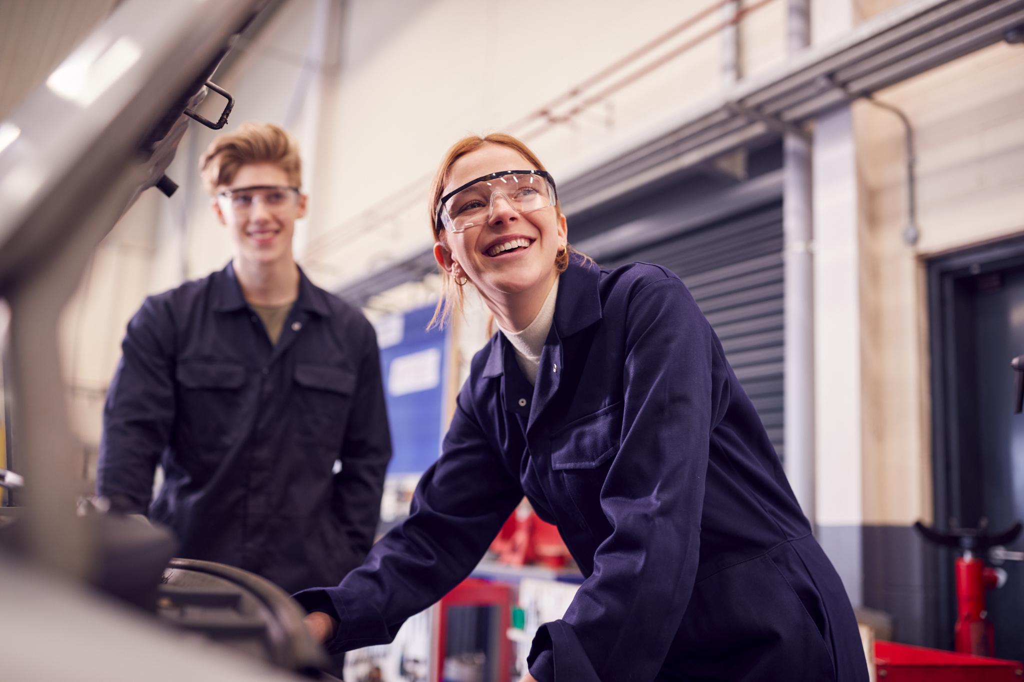 Two automotive students smiling in an automotive shop