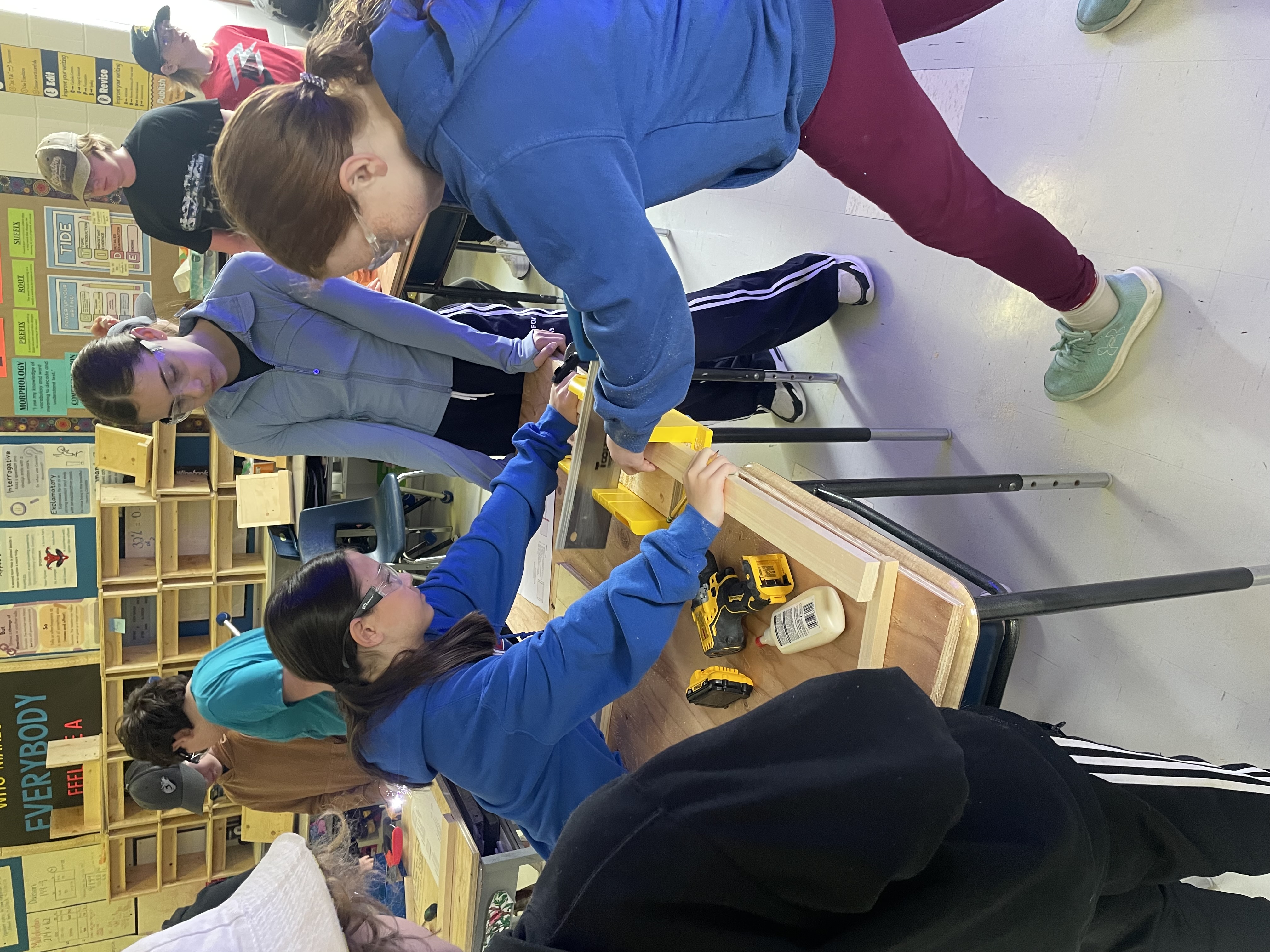 Three students work on lap desk project in their classroom