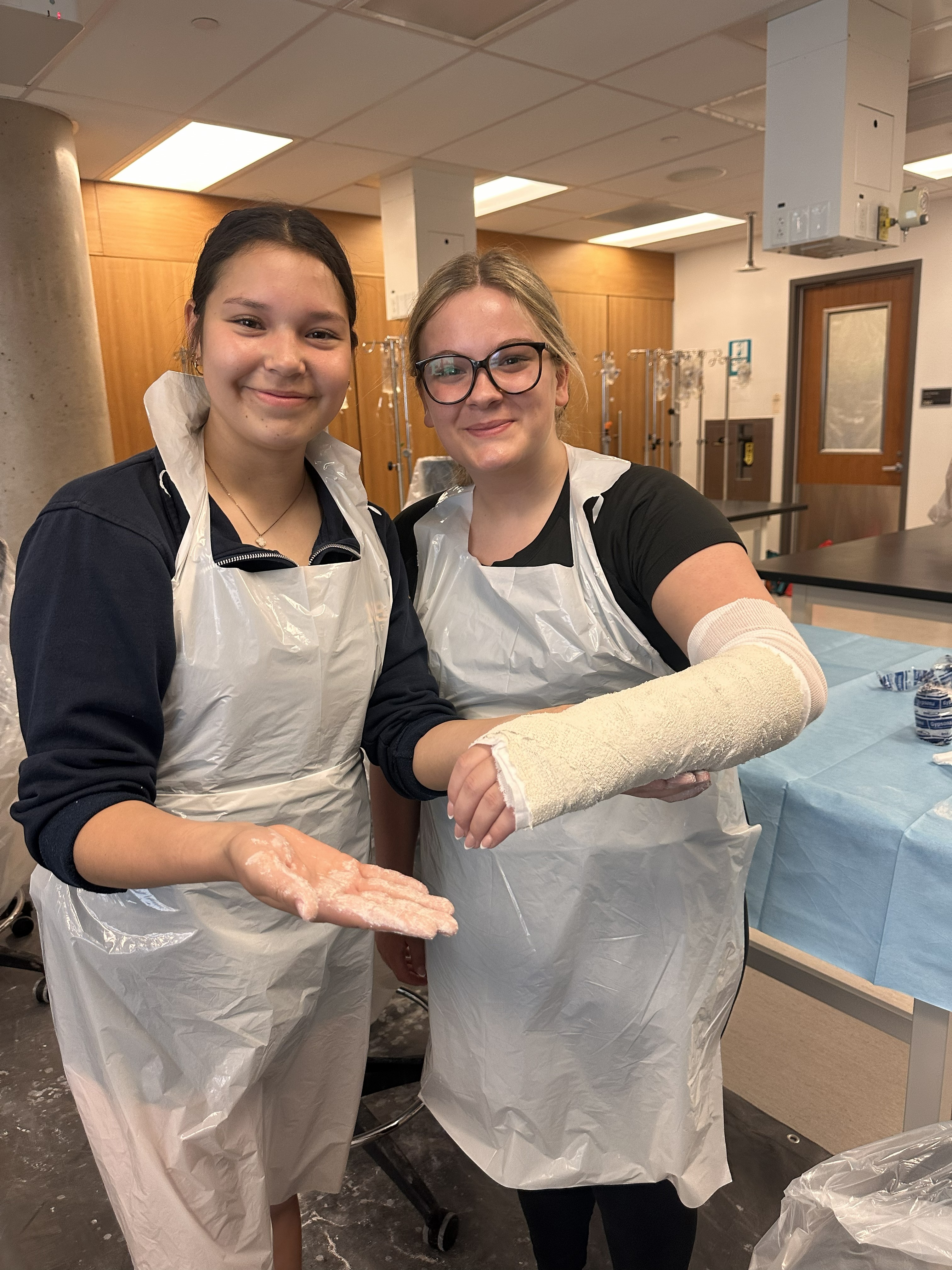 Two NDSS students who learned casting techniques at the Clinical Simulation Centre at Queen's University. One student is holding up their arm cast.
